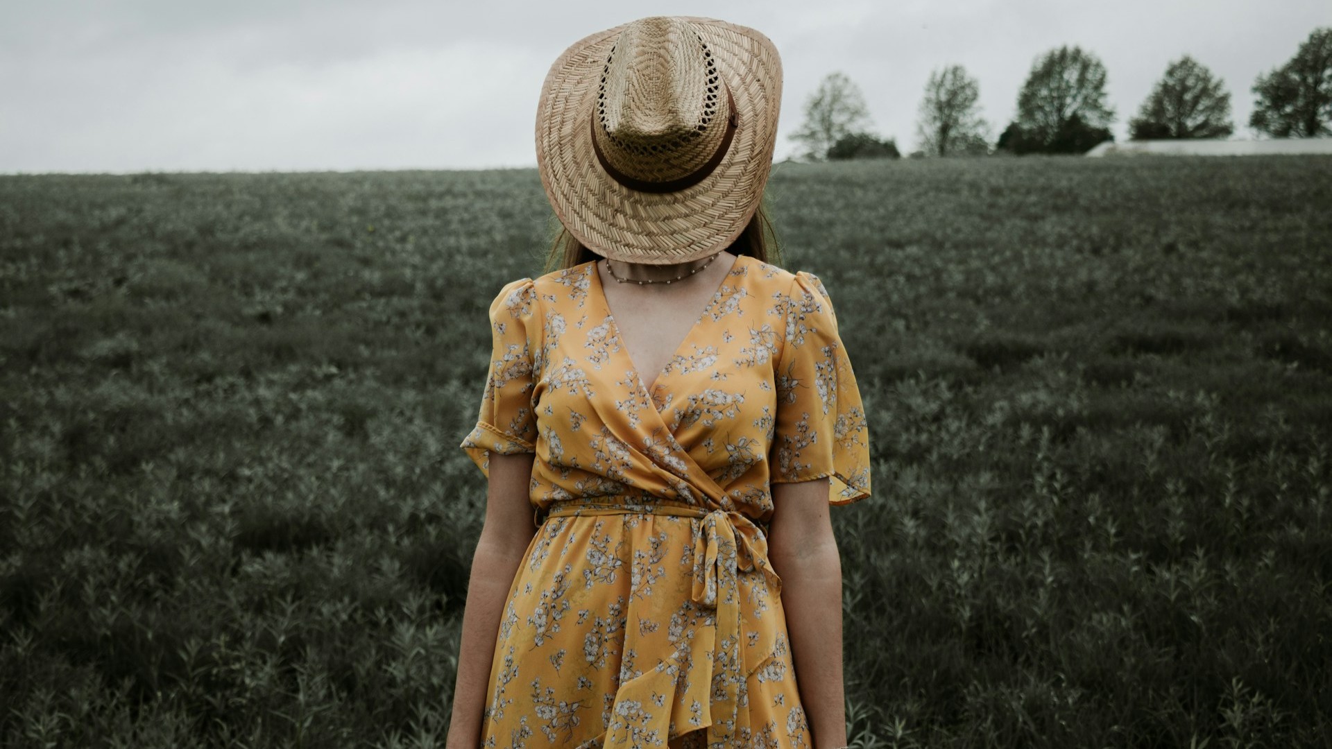 Vrouw in bloemenjurk met diepe uitsnede in open veld, jurk met rood-blauw bloemenpatroon